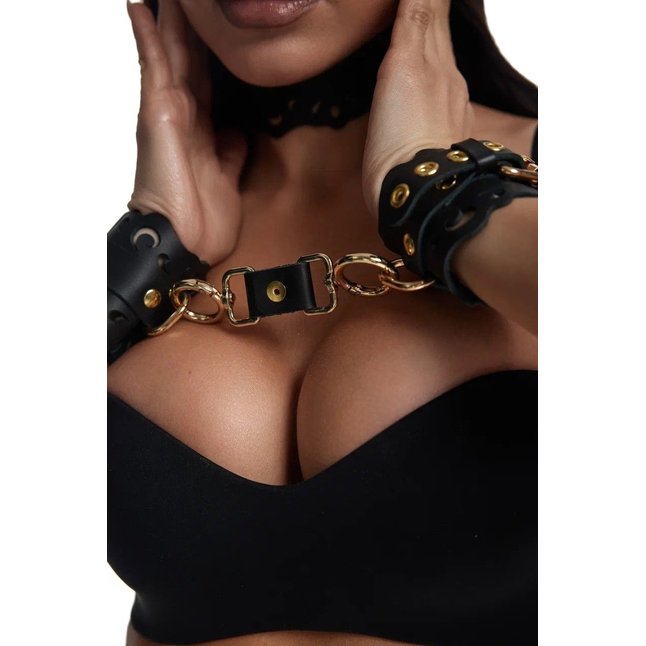 Черные кожаные наручники с узорами и золотистой фурнитурой. Фотография 4.